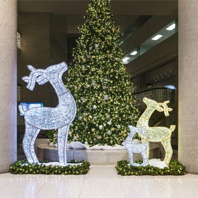 three large LED reindeer pictured in front of a pre-lit artificial Christmas tree