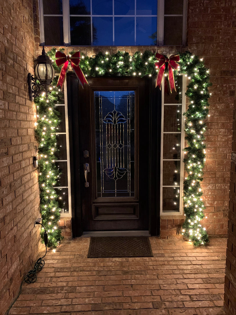 Picture of a doorwat decorated with led mini lights on garland and red bows