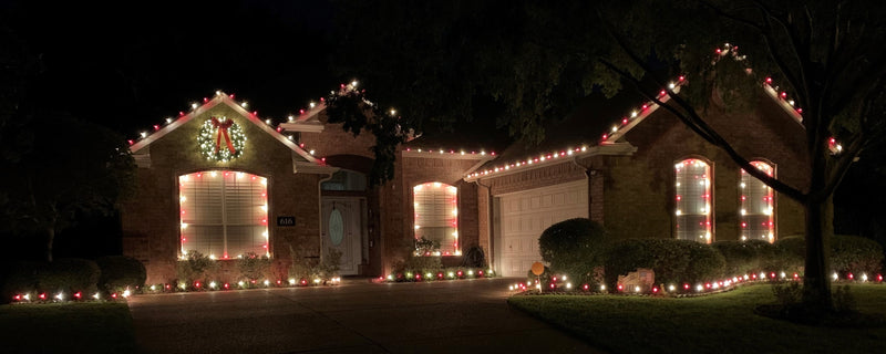 Pictue rof a house decorated in red and white C9 bulbs and a wreath with bows and lights