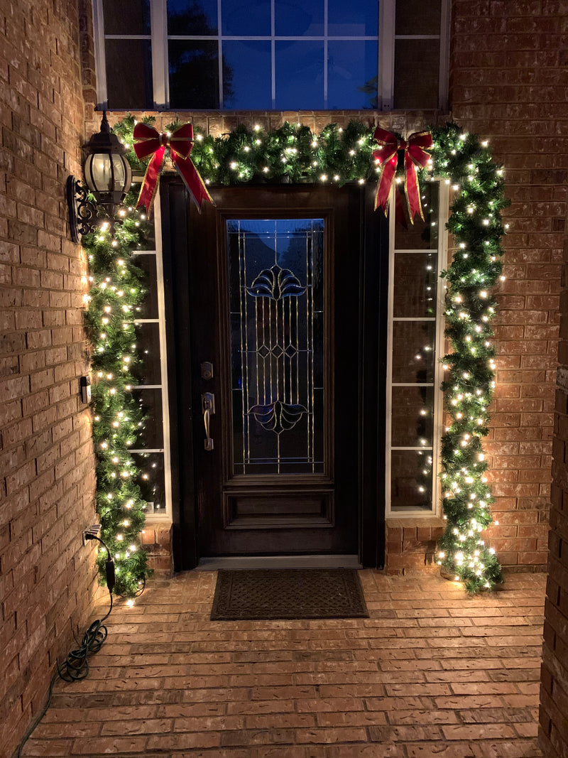 picture of a decorated doorway with lit garland and bows